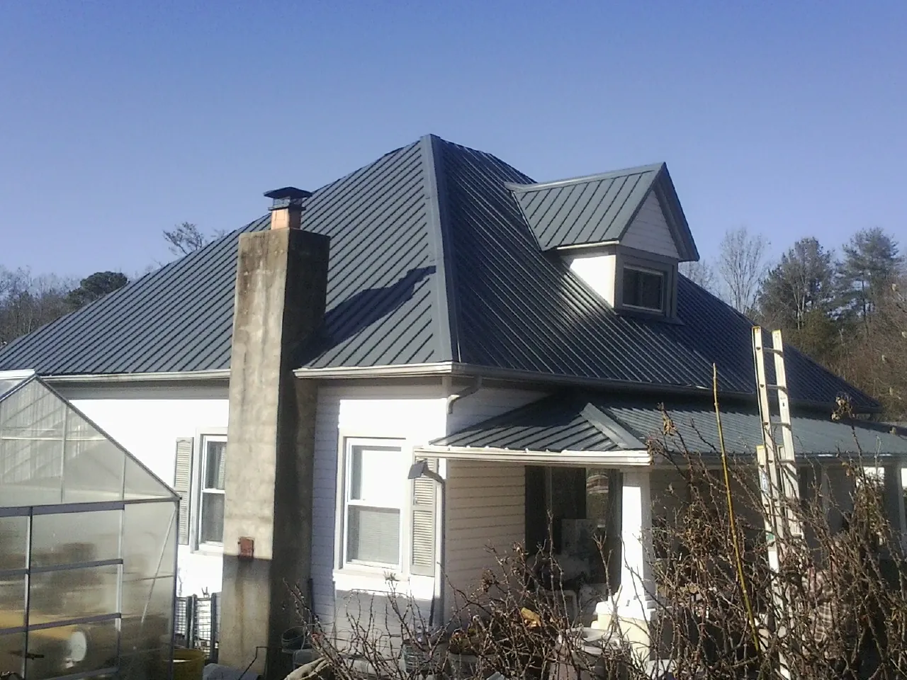 Dark blue standing seam metal roof on a white farmhouse with dormer — Slate & Tile Roof Repair by Roofing Brothers in Menlo Park