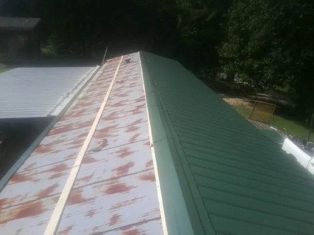 Old rusted panels beside newly installed green metal roofing — Wind Damage Roof Repair by Roofing Brothers in Menlo Park