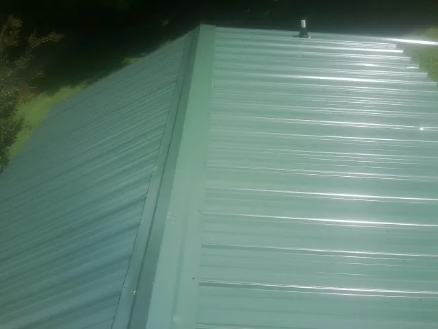 New green metal panels meeting at the ridge of a roof — Flat Roof Repair work by our crew in Menlo Park