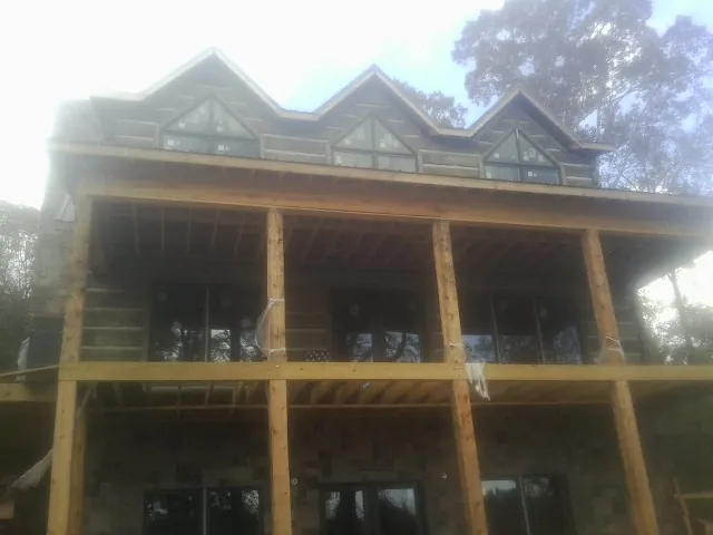 Dormers and porch framing on a large log home under construction — Roof Coating work by our crew in Menlo Park