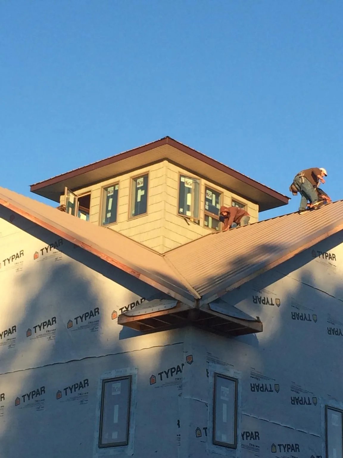 Roofers working around a rooftop cupola on a new metal roof at sunset — Roof Waterproofing in Menlo Park by Roofing Brothers